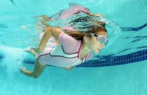 Девочка плавает в бассейне