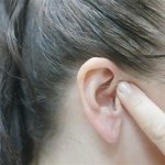 Девушка пальцем прикрывает ухо