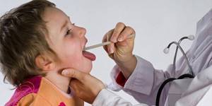Доктор осматривает горло ребенка, заболевшего ларингитом