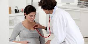 Доктор слушает легкие беременной женщины